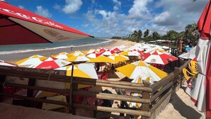 Ein Strand mit Sonnenschirmen und einem Holzzaun.