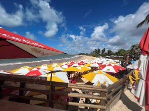 Ein Strand mit Sonnenschirmen und einem Holzzaun.