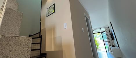 A staircase with a handrail, a wall-mounted light fixture, and a door leading to an outdoor area.