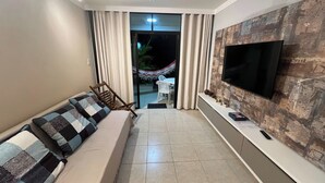 Ein Wohnzimmer mit einer Couch, einem Fernseher und Blick ins Freie.