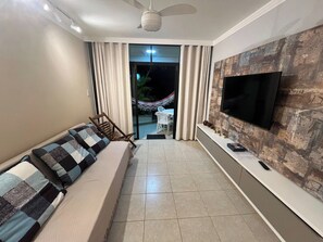 Ein Wohnzimmer mit einer Couch, einem Fernseher und Blick ins Freie.
