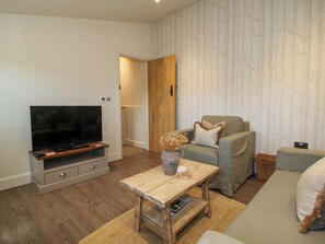Una sala de estar con televisor, sofá y mesa de centro.