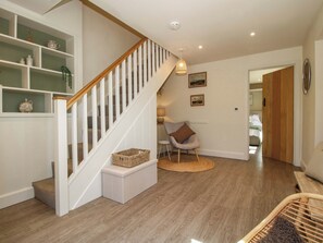 Una escalera con barandillas blancas y un pasamanos de madera que lleva a una habitación con cama y sillón.