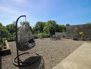 A garden patio with a hanging chair, a table with chairs, and a wooden fence. - Thyme Away (Bucknell)