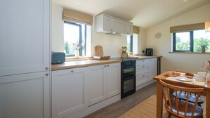 Eine moderne Küche mit weißen Schränken, einem eingebauten Backofen und einem Essbereich mit Holztisch und -stühlen.