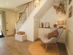 A staircase with white railings, a woven rug, a cushioned chair, and a wall-mounted lamp. - Thyme Away (Bucknell)
