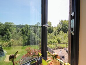 A window with a view of a garden and a metal latch. - Thyme Away (Bucknell)