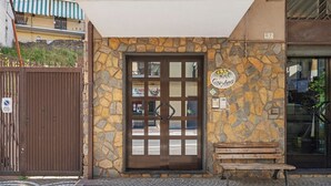 Fachada de piedra con una puerta de madera, un banco en el exterior y un cartel sobre la puerta.
