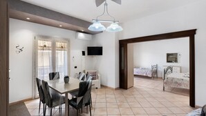 Un comedor con una mesa y sillas, un ventilador de techo y un televisor en la pared.