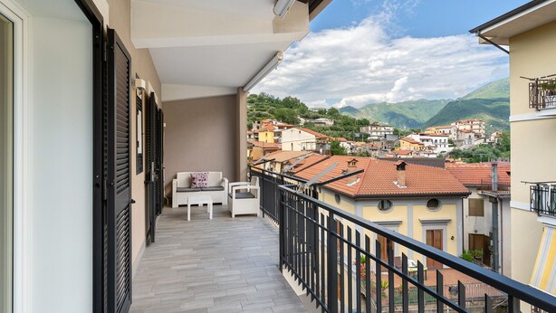 Un balcón con vista a un pueblo, un sofá blanco y una mesa.
