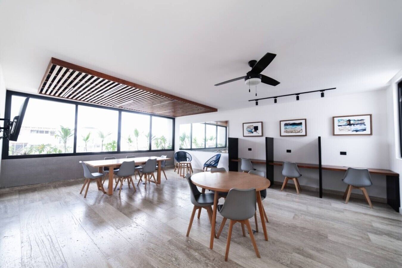 Une salle de conférence moderne, dotée de grandes fenêtres, d’un ventilateur de plafond et d’œuvres d’art accrochées aux murs.