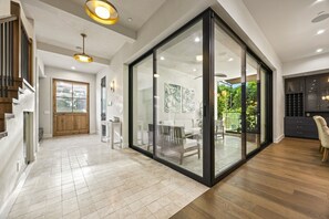 Ein modernes Interieur mit Glastrennwand, Holzboden und einer Essecke mit Stühlen und Tisch.