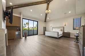 Ein geräumiges Schlafzimmer mit einem großen Bett, einem Schreibtisch und Blick ins Freie.