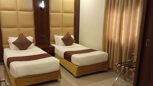 A hotel room with two beds, a wooden headboard, a small table, and a chair. - ROYALTY GROUP (Riyadh)
