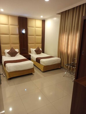 A hotel room with two beds, a wooden headboard, a small table, and a chair.