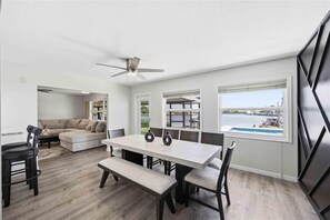 A modern interior with a dining area, a sofa, and a view of a body of water. - Waterfront beauty in Overbrook Gardens (Englewood)