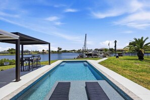 A swimming pool with a covered patio area, a view of the water, and a distant view of a marina. - Waterfront beauty in Overbrook Gardens (Englewood)