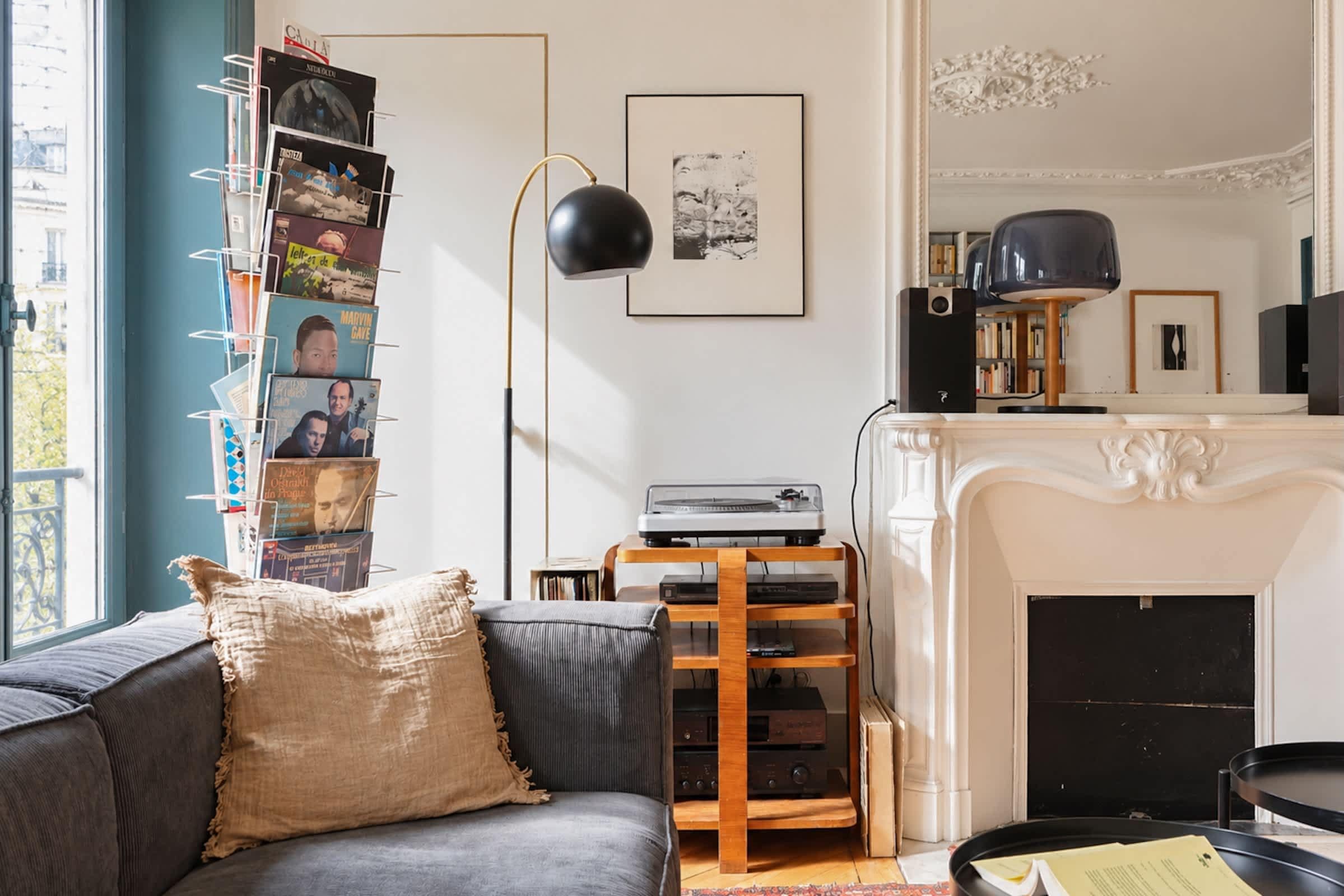 A living room with a sofa, a fireplace, a record player, and a bookshelf.