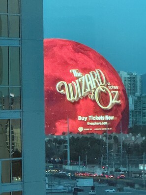Eine große Werbung für 'The Wizard of Oz' mit rotem Hintergrund und goldener Schrift.
