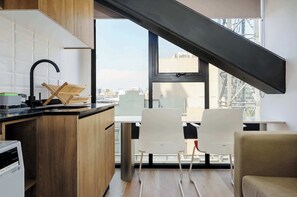 Eine moderne Küche mit einem schwarzen Wasserhahn, Holzausziehtischen und einem Fenster mit Blick auf eine Stadtlandschaft.