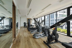Ein Fitnessstudio mit Trainingsgeräten, großen Fenstern und Holzboden.