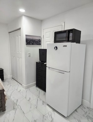 A compact kitchen with a white refrigerator, a microwave, and a black cabinet. - Efficiency near Tampa airport and Raymond James Stadium. Parking & Private Entry (Tampa)