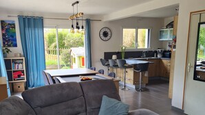 Een moderne woonkamer met een hoekbank, een eethoek en een keuken.