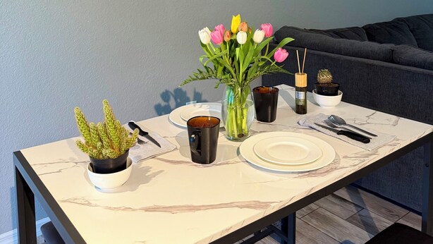 Una mesa de comedor con un jarrón de tulipanes, una vela y una botella de vino.