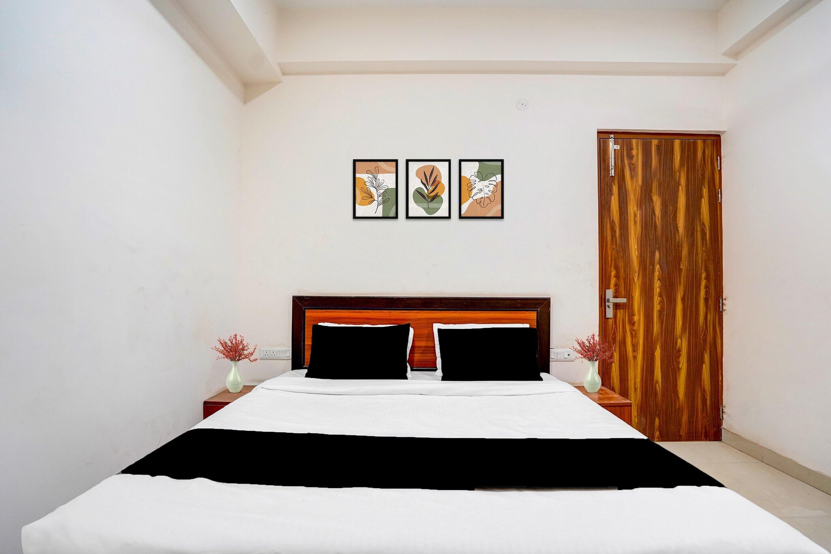 A bedroom with a wooden headboard, a bed with white bedding, two nightstands with vases, and a wooden door.