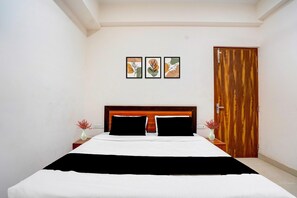 A bedroom with a wooden headboard, a bed with white bedding, two nightstands with vases, and a wooden door.