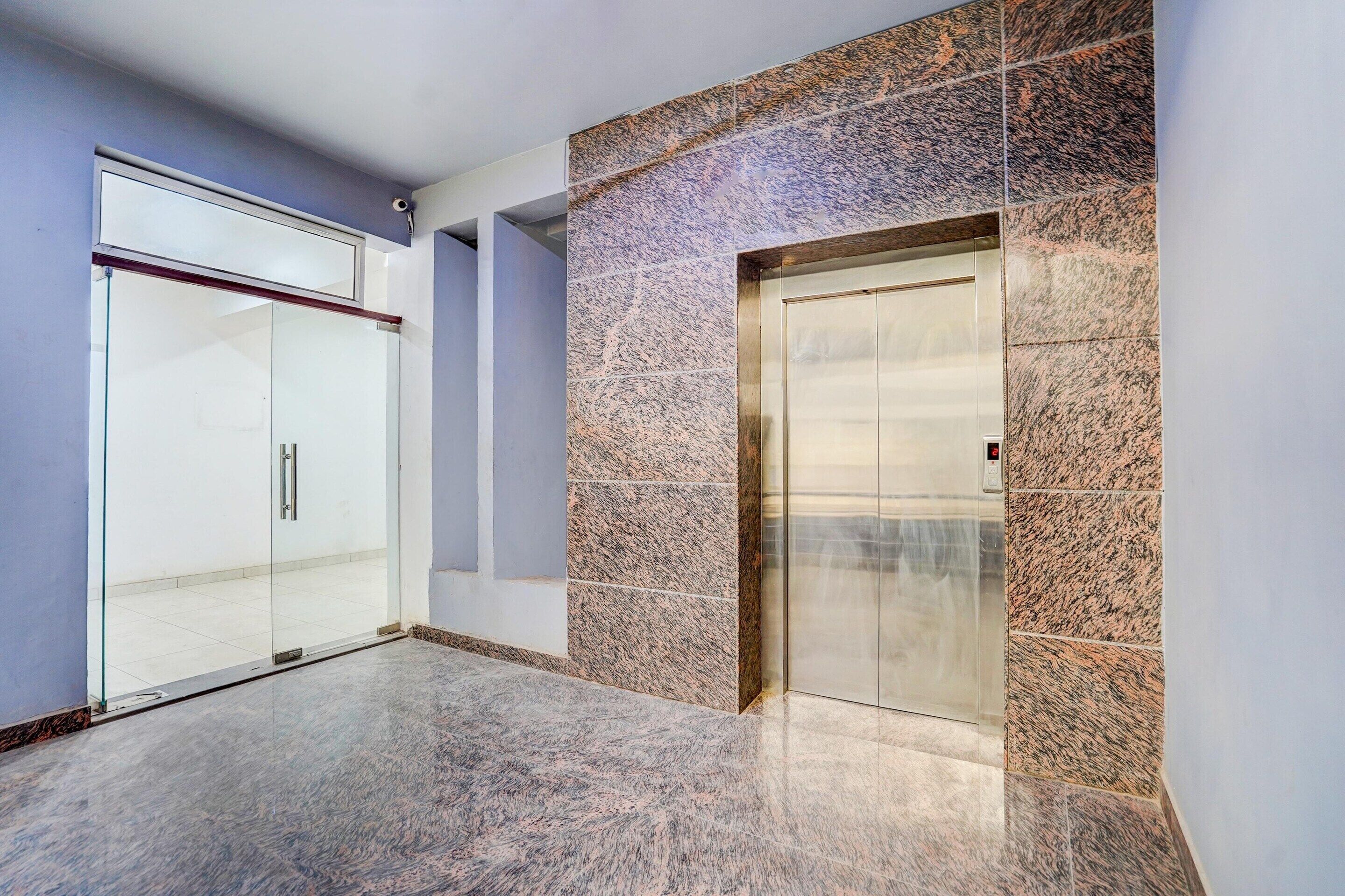 A modern elevator with a digital display, adjacent to a glass door entrance.
