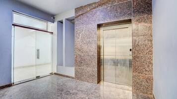 A modern elevator with a digital display, adjacent to a glass door entrance.