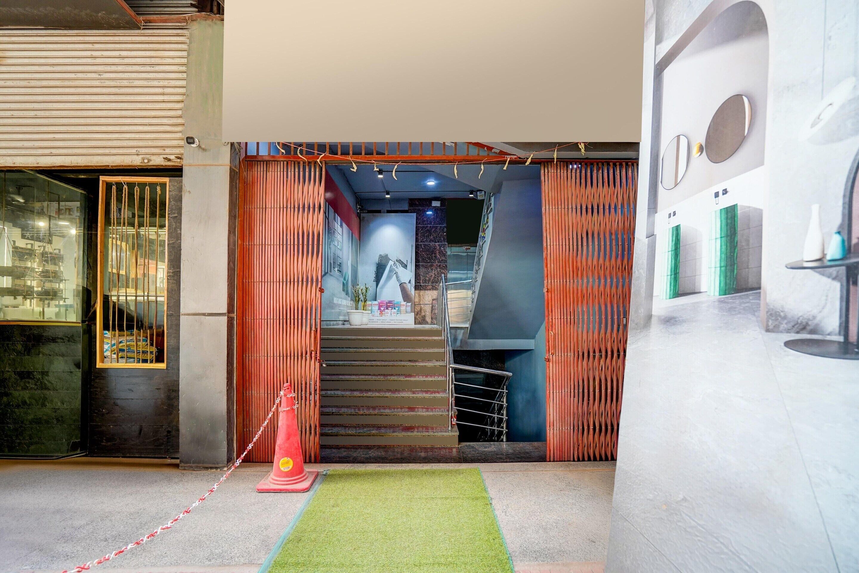A hotel lobby with a staircase leading to a second floor, a reception desk, and a glass partition with a view of the street.
