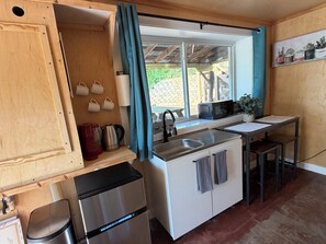 Eine kleine Küche mit Spüle, Mikrowelle und Kühlschrank.