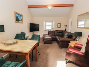 Ein Wohnzimmer mit einem Holztisch, grünen Stühlen, einem braunen Ledersofa und einem roten Ledersessel.