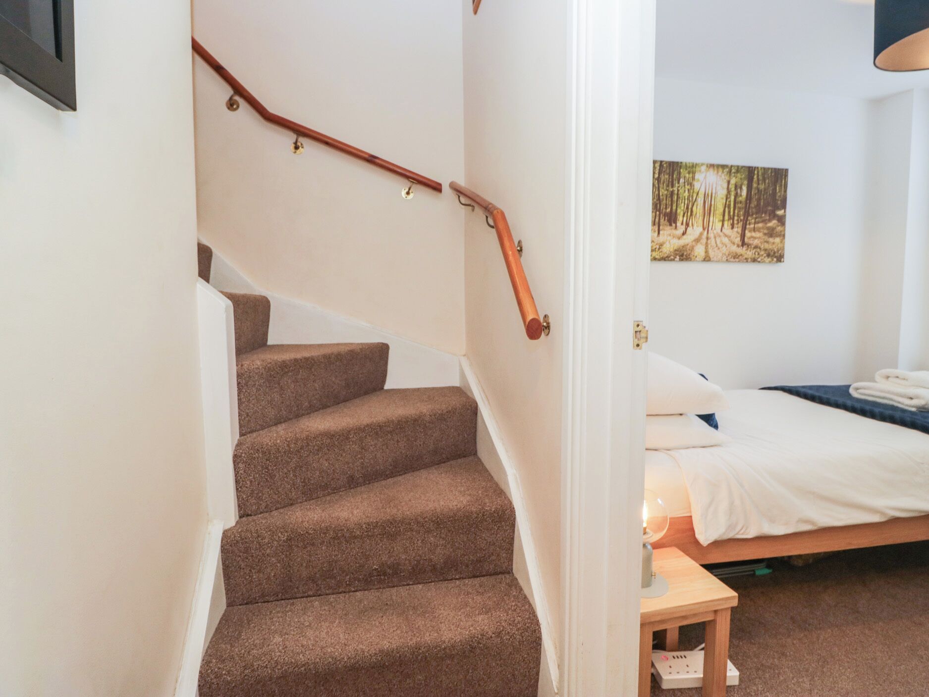 Ein Schlafzimmer mit einem Bett, einem kleinen Nachttisch und einer Treppe mit einer Holzhandläufe.