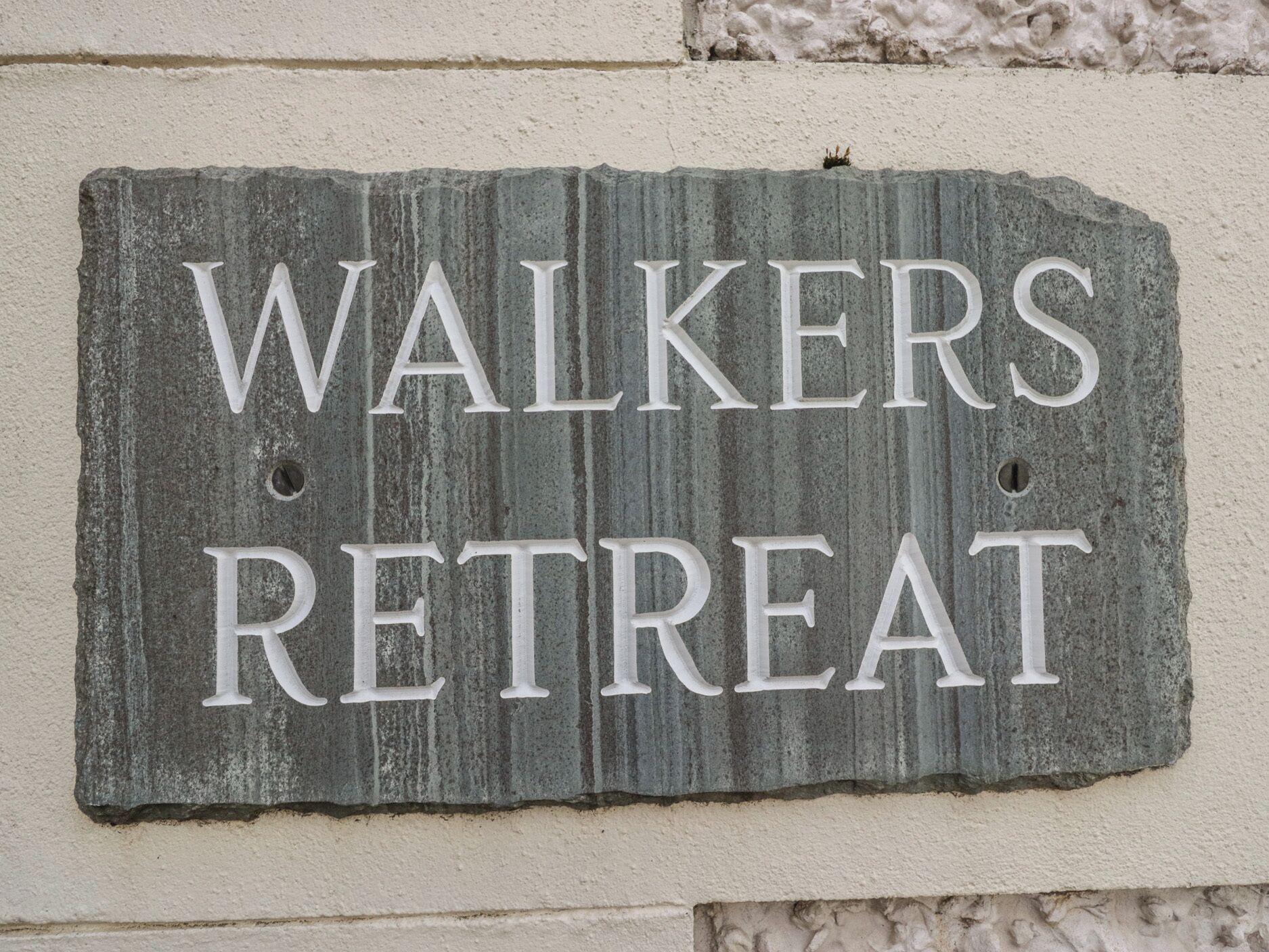 A rustic sign with the words 'WALKERS RETREAT' on a textured stone background.