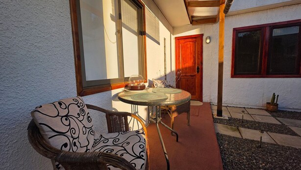A patio with a round table, wicker chairs, and a red door. - Oceana Suites Bosques de Montemar (Concón)
