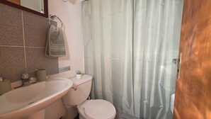 A bathroom with a sink, toilet, and shower curtain. - Oceana Suites Bosques de Montemar (Concón)