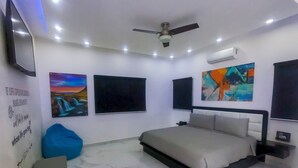 Camera da letto con un letto, una ventola a soffitto, illuminazione a incasso, condizionatore d'aria a parete e opere d'arte.
