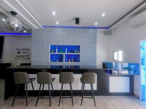 A modern bar area with a central counter, three bar stools, and shelves with bottles. - Exclusive 6BR Punta Cana Villa w/ 2 Jacuzzis & Private Lounge & Staff (Punta cada)