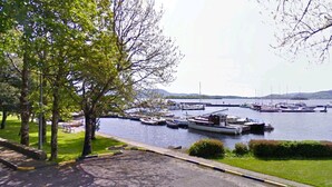 A marina with boats docked, a bridge in the background, and trees along the water's edge. - Cosy Lakeside Retreat in Mountshannon (Mountshannon)