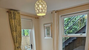 A bedroom with a bed, a window with a view of a staircase, a door leading to an outdoor area, and a hanging light fixture. - Cosy Lakeside Retreat in Mountshannon (Mountshannon)