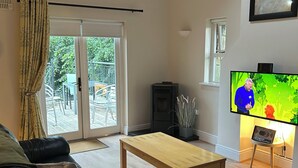A living room with a sofa, a coffee table, a television, and a fireplace. - Cosy Lakeside Retreat in Mountshannon (Mountshannon)