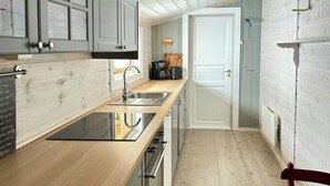 Een kleine keuken met houten aanrechtbladen, roestvrijstalen apparatuur en een kleed.