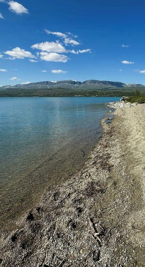 Ein klarer See mit steiniger Uferlinie und fernen Bergen.