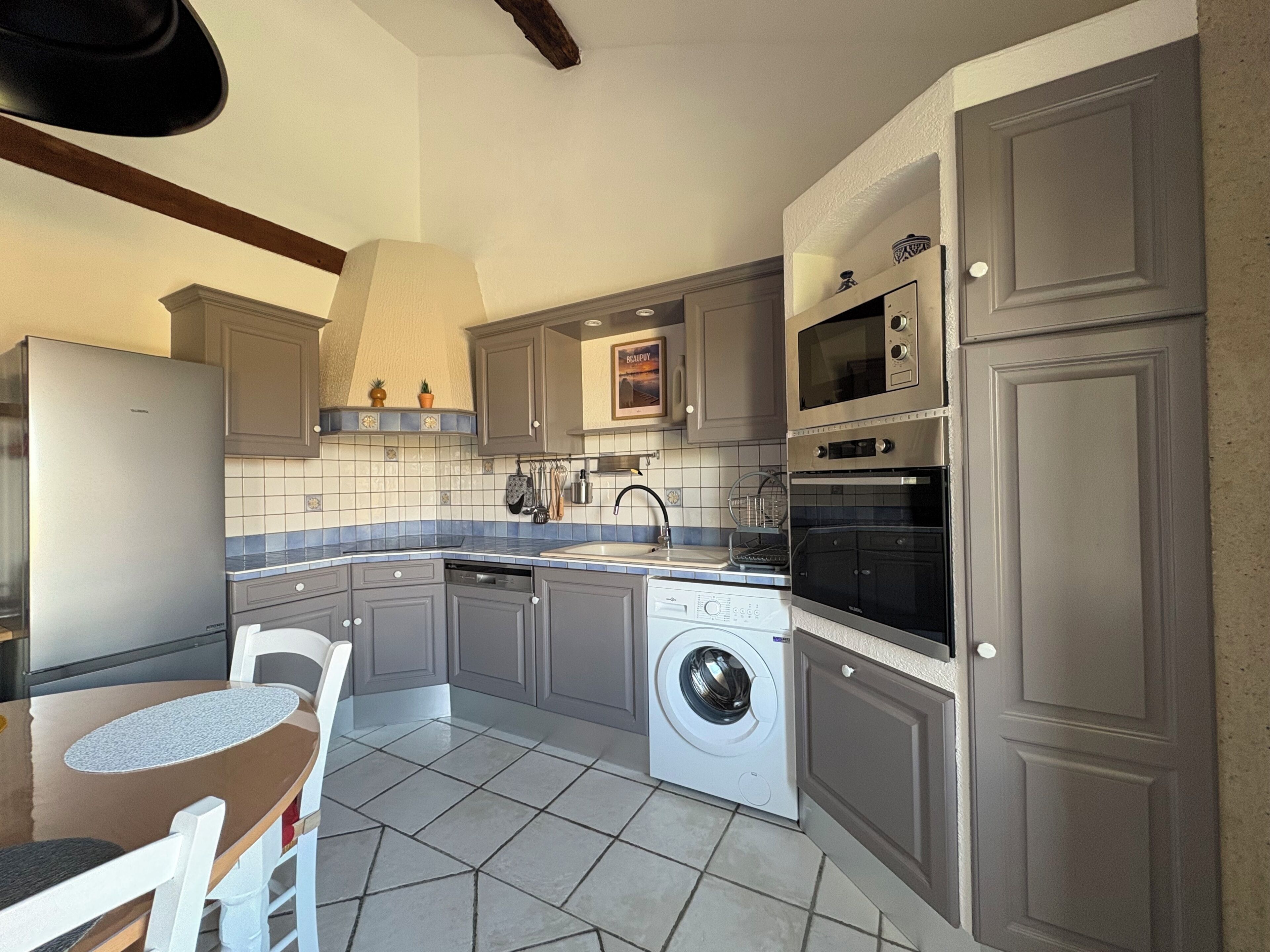A kitchen with grey cabinets, a washing machine, a microwave, and a sink.