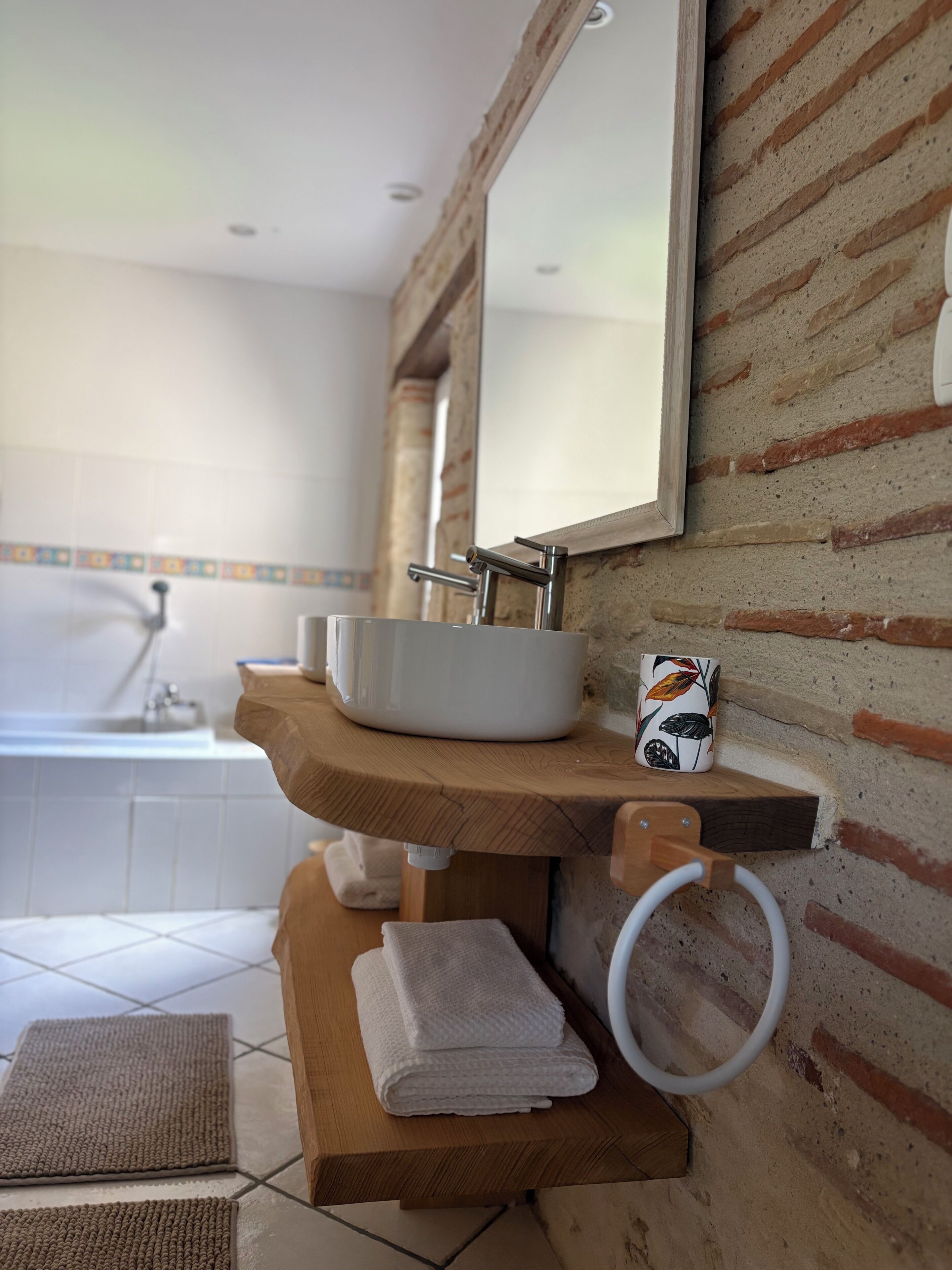 A bathroom with a sink, mirror, towel rack, and a decorative mug.