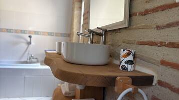 A bathroom with a sink, mirror, towel rack, and a decorative mug.