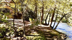 Un cadre naturel en plein air comprenant un chalet en bois, un sentier pavé de pierres et une rivière.